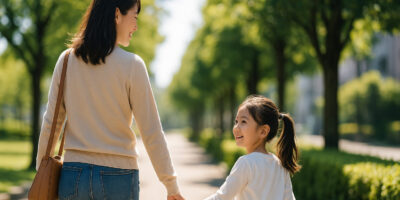 明るい表情で子供と手を繋いで歩く母親の後ろ姿、希望に満ちた新しいスタートをイメージした画像